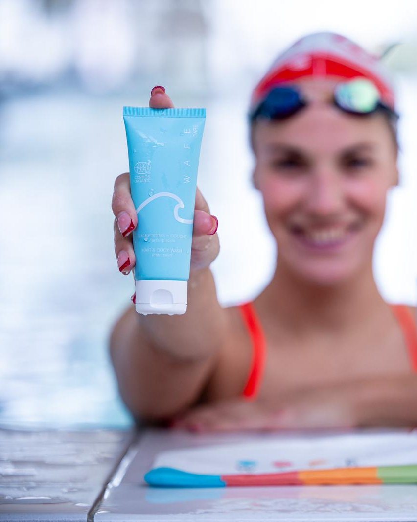 Caroline Jouisse tend le shampooing-douche WAFE Care au bord du bassin
